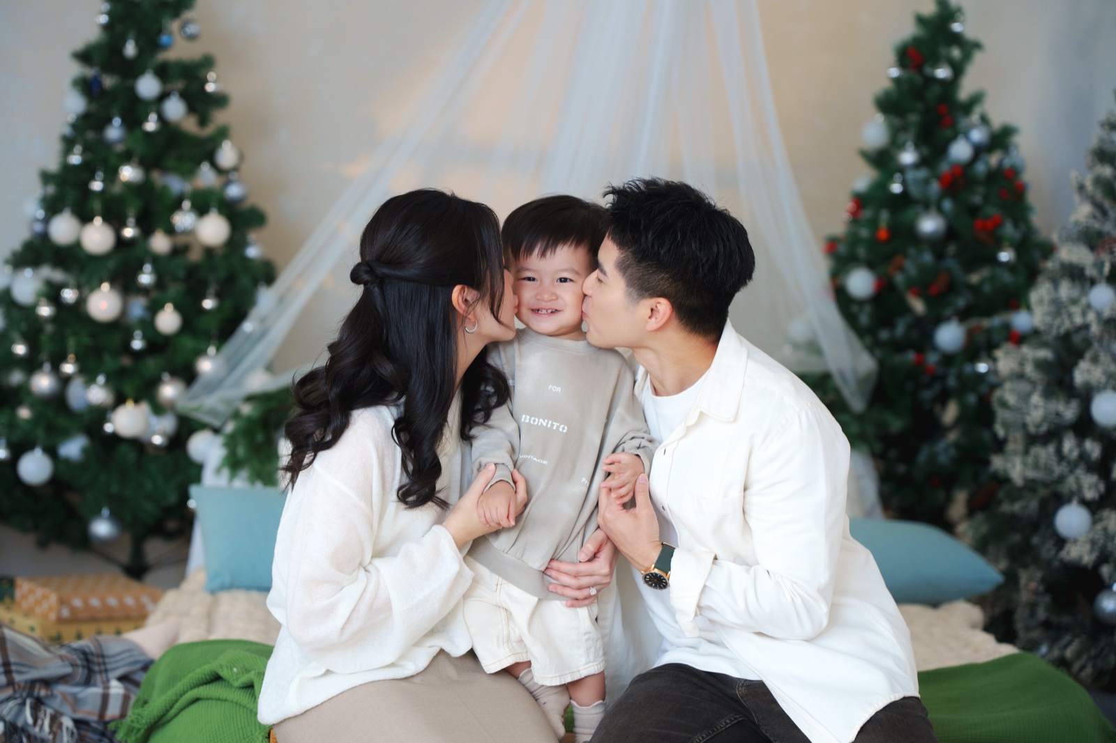 Chloe 與 Hansen 在聖誕樹之間親吻小朋友的臉頰