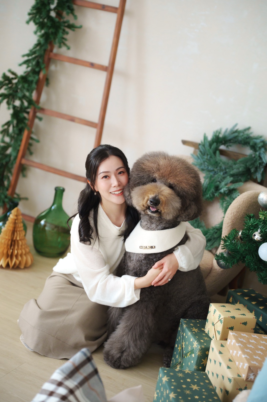 Chloe 在聖誕佈置和禮物旁抱着愛犬合照