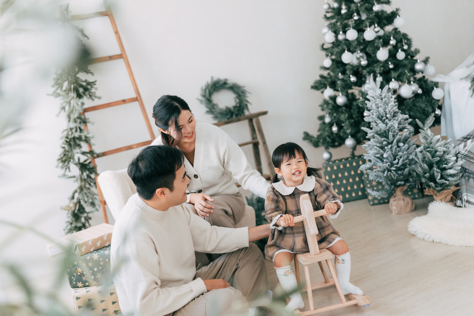 Lyla 一家在聖誕樹旁與木製搖搖馬合照