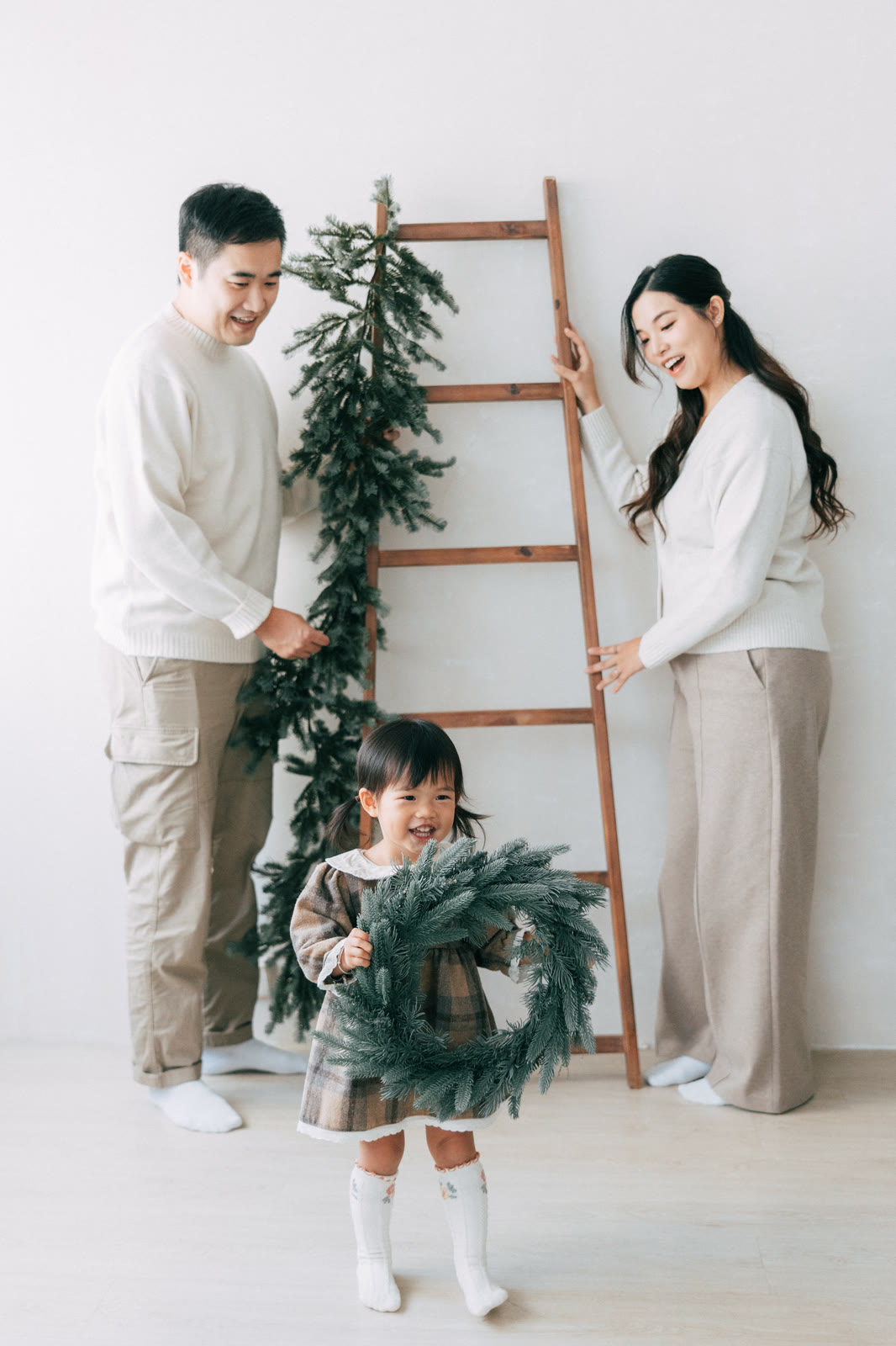 小朋友拿着聖誕花環站在家人身前
