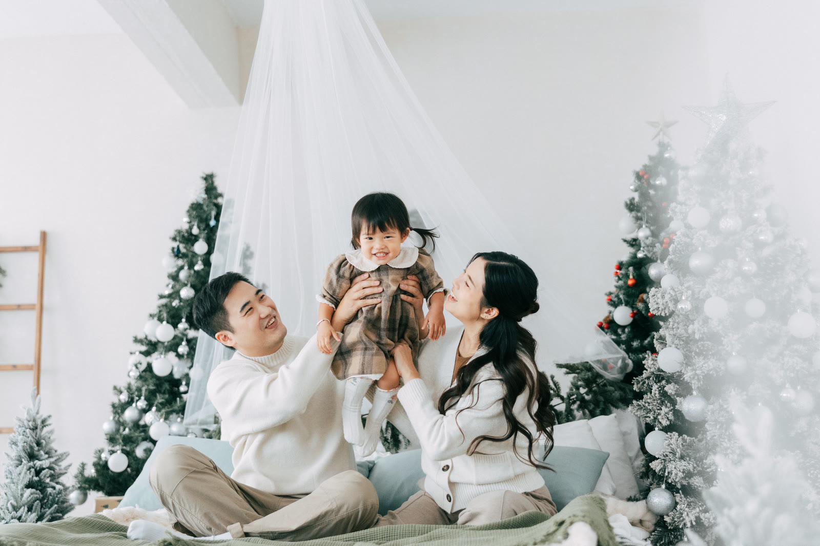 Lyla 一家三口在聖誕樹前舉起小朋友合照