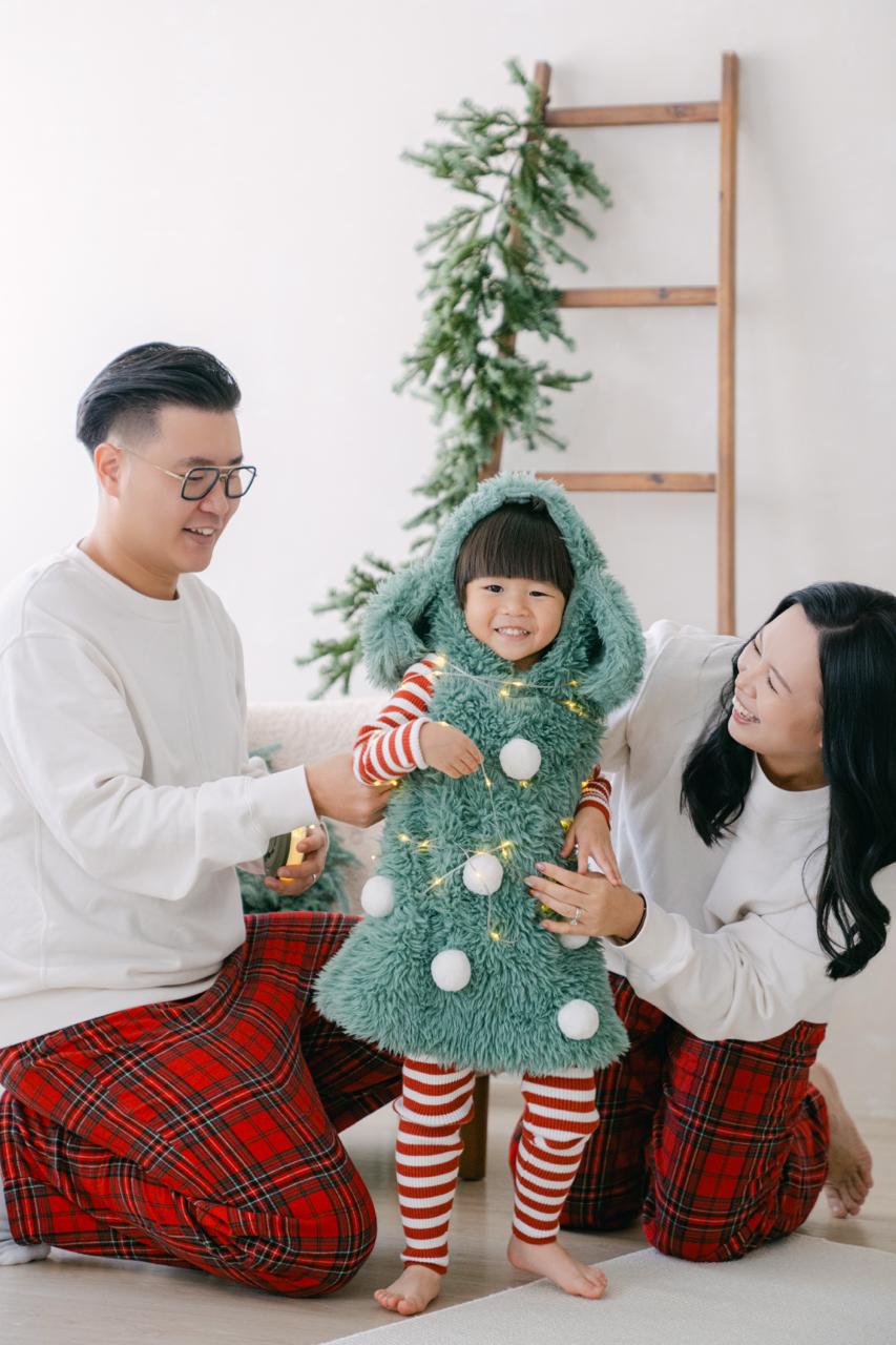 YatYat 一家在聖誕場景中合照,小朋友穿着聖誕樹造型服裝